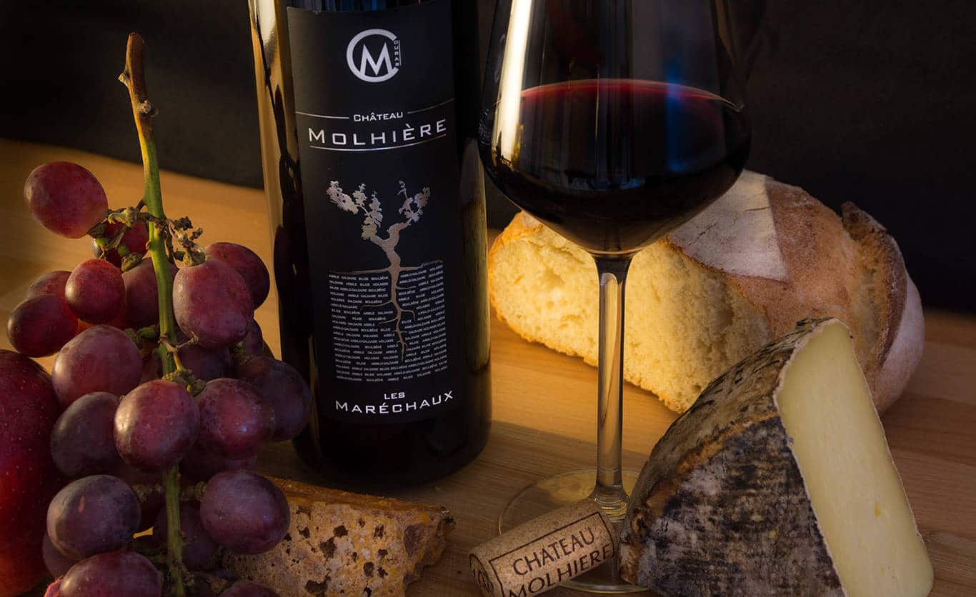 A bottle of Les Maréchaux red wine, a glass of wine, grapes and cheese